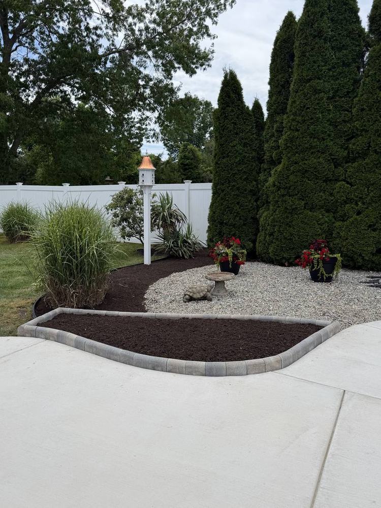 Paver-edged mulch bed with garden accents